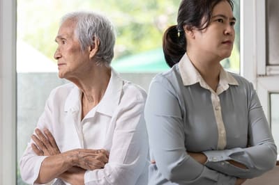 An elderly woman and caregiver looking pensive.