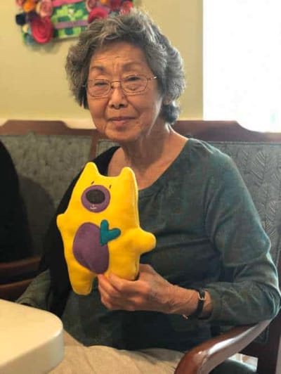 Senior resident holding a colorful plush toy.