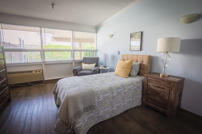 A cozy furnished resident room with natural light