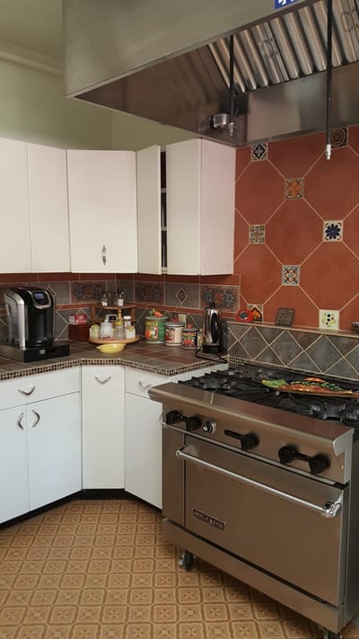 A kitchen area with appliances and colorful tiles