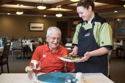 Staff serving a meal to a resident in the dining room