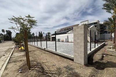 Construction site with newly poured concrete and fencing.