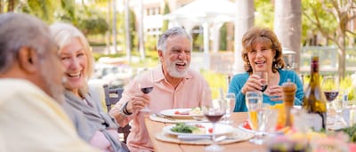 Seniors enjoying a meal outdoors with drinks