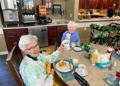 Two residents enjoying drinks at a communal dining table