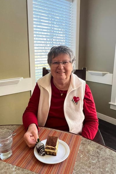 A smiling resident enjoying dessert in a dining area