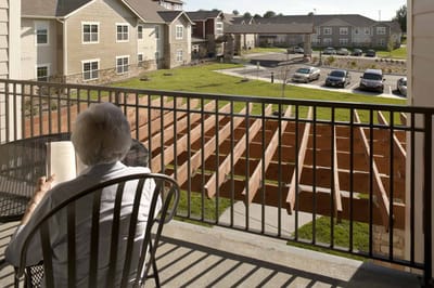 A resident reading on a balcony overlooking the grounds