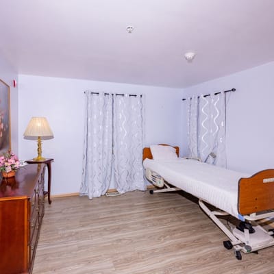 A private resident room with a bed and dresser