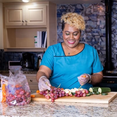 Staff member preparing fruits in a kitchen setting