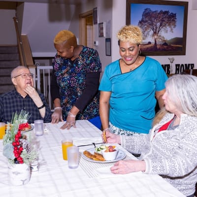 Residents enjoying a meal with staff assistance