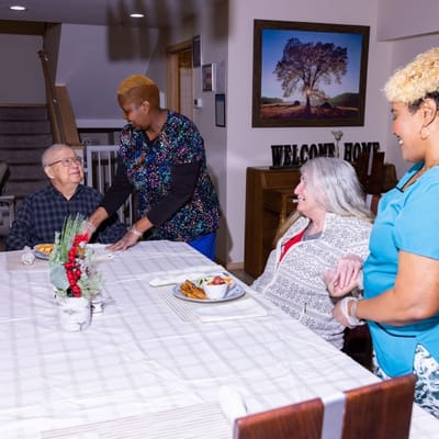 Residents enjoying a meal with staff in a dining area