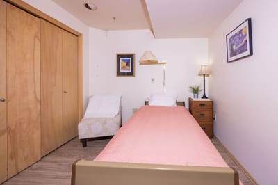 A cozy private resident room with a bed and nightstand