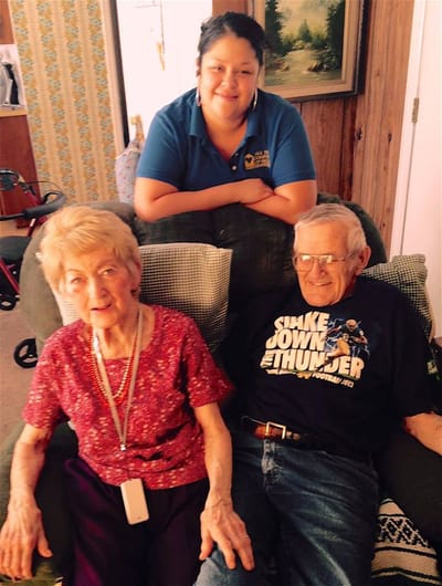 Two residents smiling with a staff member in a cozy setting