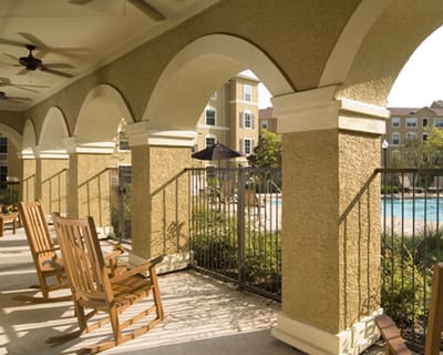 Outdoor patio area with rocking chairs and pool view