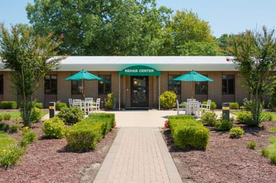 Exterior view of a rehab center with green umbrellas