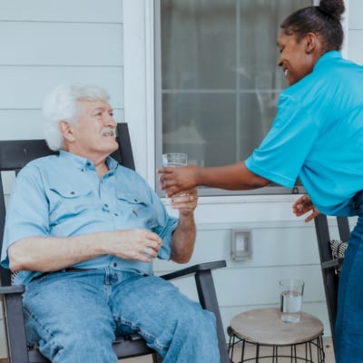 Caregiver assisting a senior gentleman with a drink