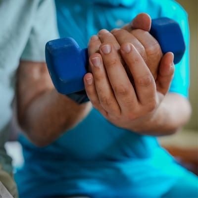Close-up of hands holding a blue dumbbell during exercise