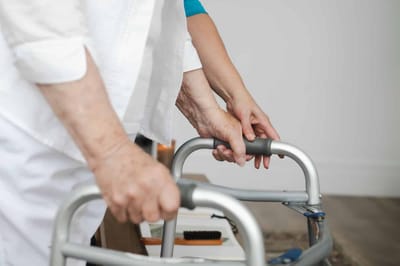 Caregiver assisting an older adult with a walker
