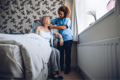 Staff assisting a resident in a cozy bedroom