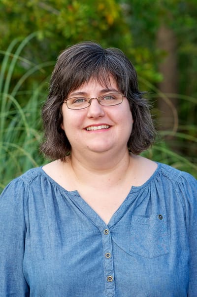 Smiling staff member in a garden setting