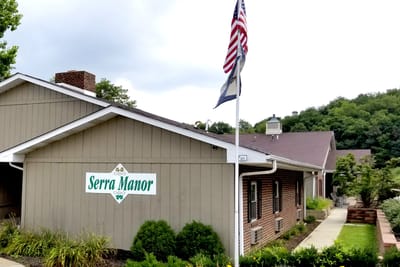 Exterior view of Serra Manor with flag.
