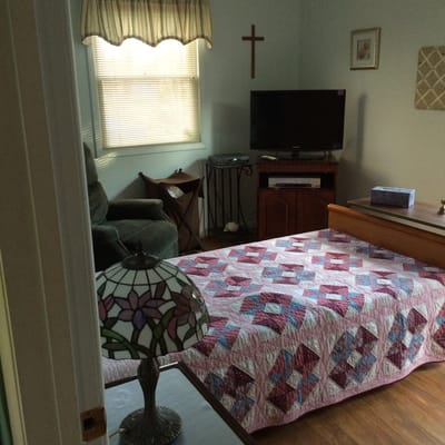 Cozy resident room with quilt and TV.