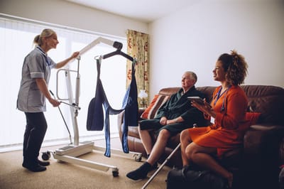 Care staff assisting a resident in a living area.