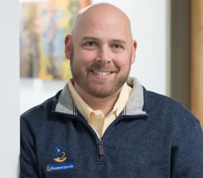 Smiling man in a polo shirt, inside a facility