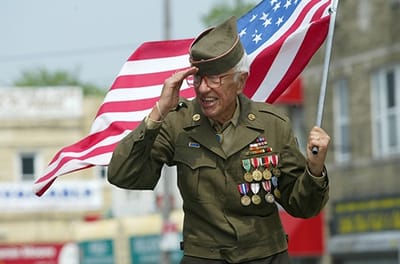 Veteran saluting with an American flag at a celebration.