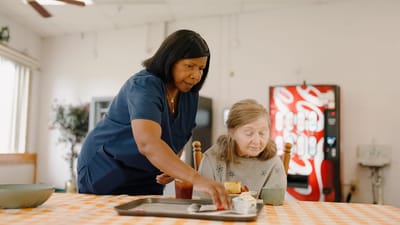 Caregiver assisting elderly resident with food.