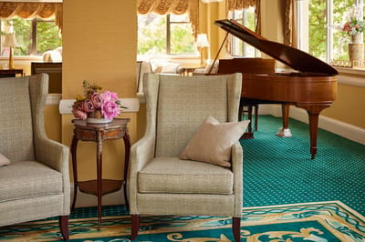 Brandywine The Savoy, assisted living in Queens, NY — Comfortable seating area with floral arrangement and piano