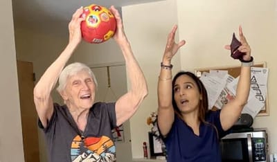 Senior resident and staff member playing with a ball indoors