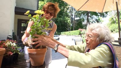 A staff member assisting a resident with planting flowers
