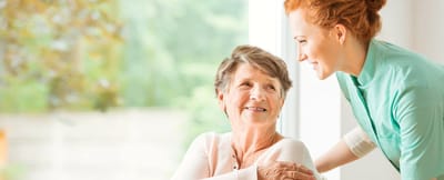 A caregiver smiling with a senior resident indoors