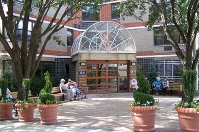 Exterior view of a senior living facility entrance with residents.