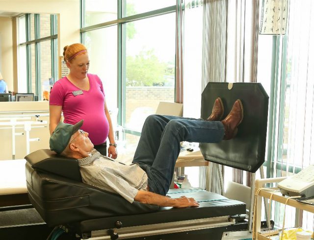 Senior man exercising with therapist in rehabilitation room