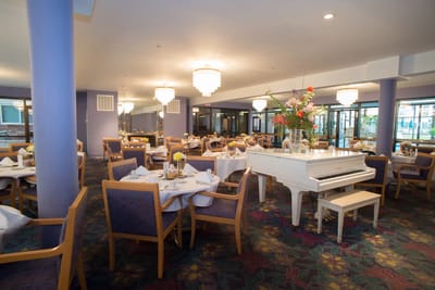 Bright dining room with white piano and floral decor