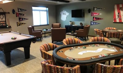 Interior view of a game room with a pool table and poker setup