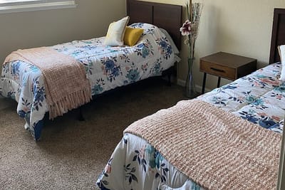 A cozy resident room with two beds and floral blankets