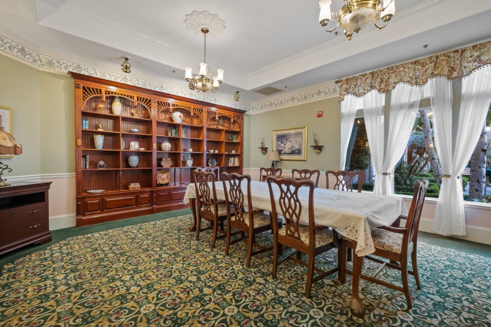 Brightly lit common area with dining table and bookshelf