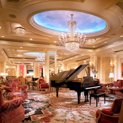An elegant common area with a grand piano and chandeliers