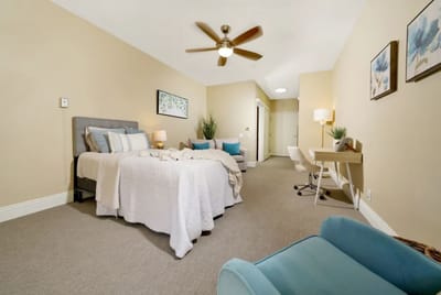 A well-furnished resident room with a bed and desk