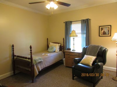 A cozy resident room with a bed and armchair