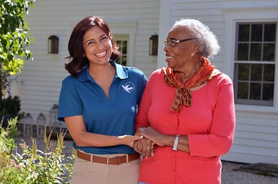 Smiling caregiver holding hands with a resident outdoors