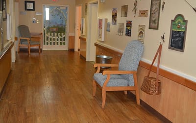 A hallway with a chair and decor in a senior care facility