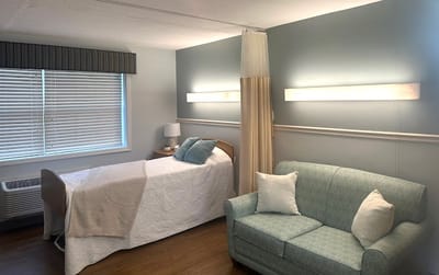 A cozy resident room with a bed and seating area