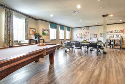 Bright activity room with a pool table and art displays