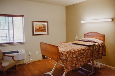 A well-furnished private resident room with a bed and chair