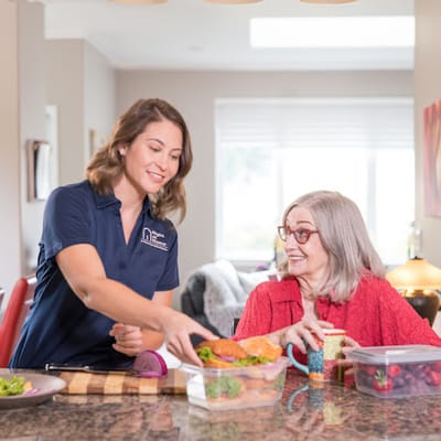 Staff member assisting a resident with meals at a dining area
