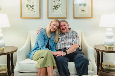 A happy resident with a family member in a cozy lounge area