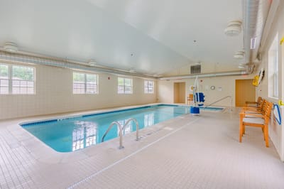 Indoor swimming pool area with chairs and windows
